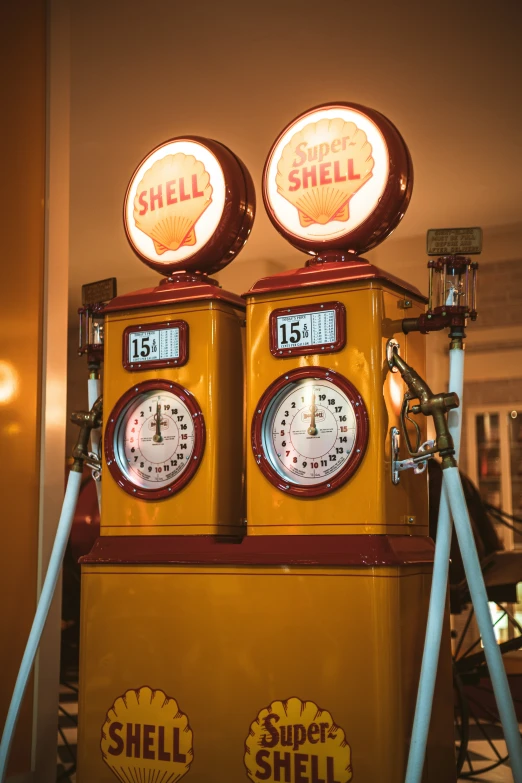 two old yellow shell shell gas pumps and some signs