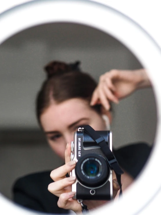 a woman taking a picture with her camera in front of a mirror