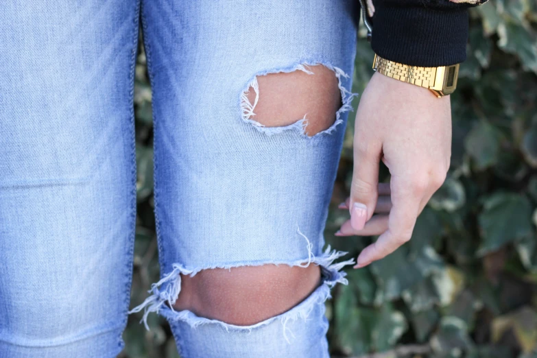 a woman in ripped jeans with a gold bang on her hand