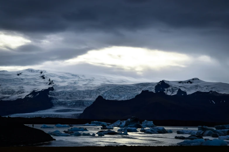 snow - covered mountains and glaciers beneath dark skies