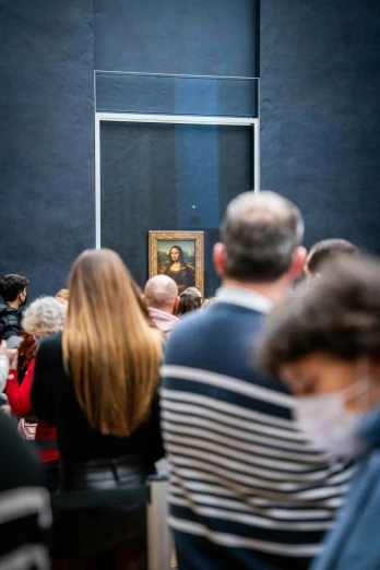 people watching a painting on display inside a room