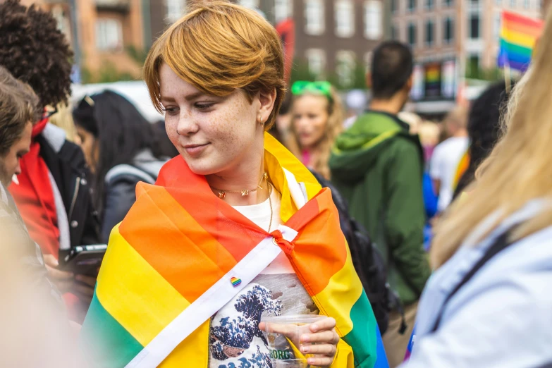 woman in a rainbow scarf holds a beverage