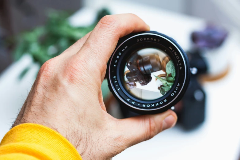 man holding a camera with reflection in the lens