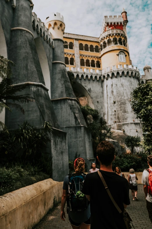 a couple of people walking past a castle in the background