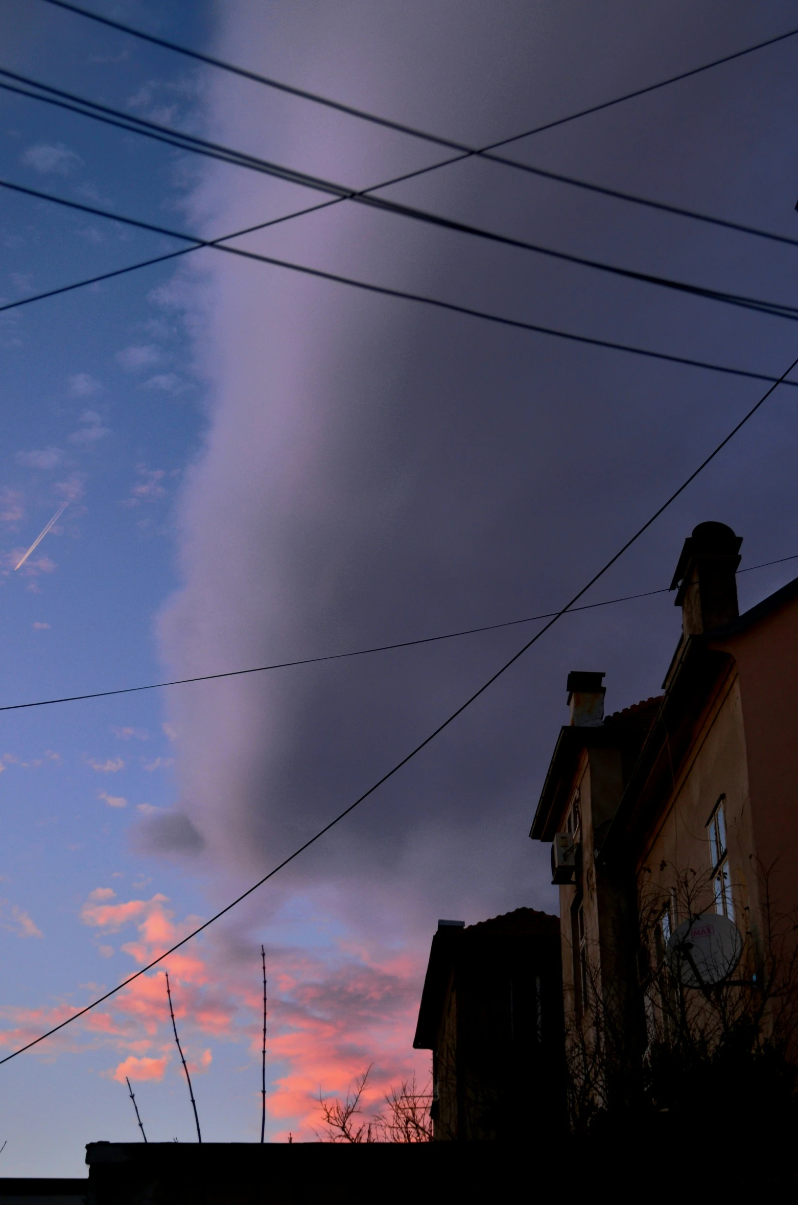 a cloudy sunset over residential buildings with telephone wires in the foreground