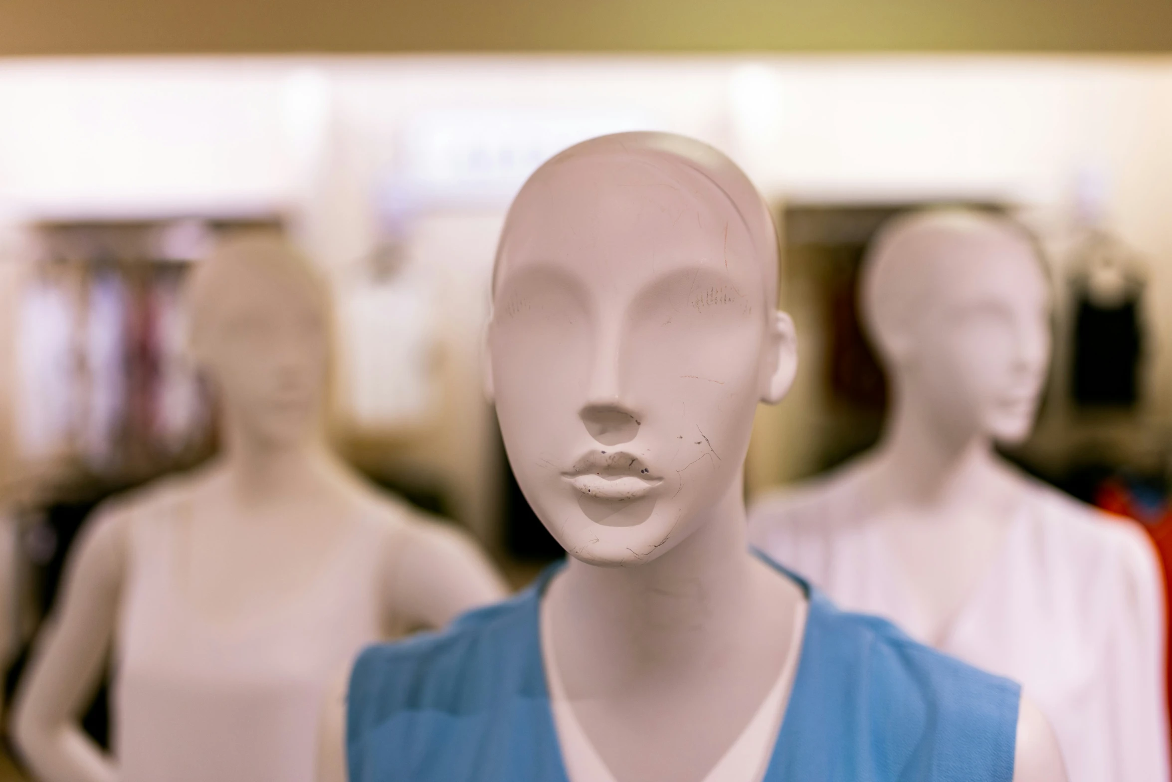 a woman's face is shown through an array of mannequin heads