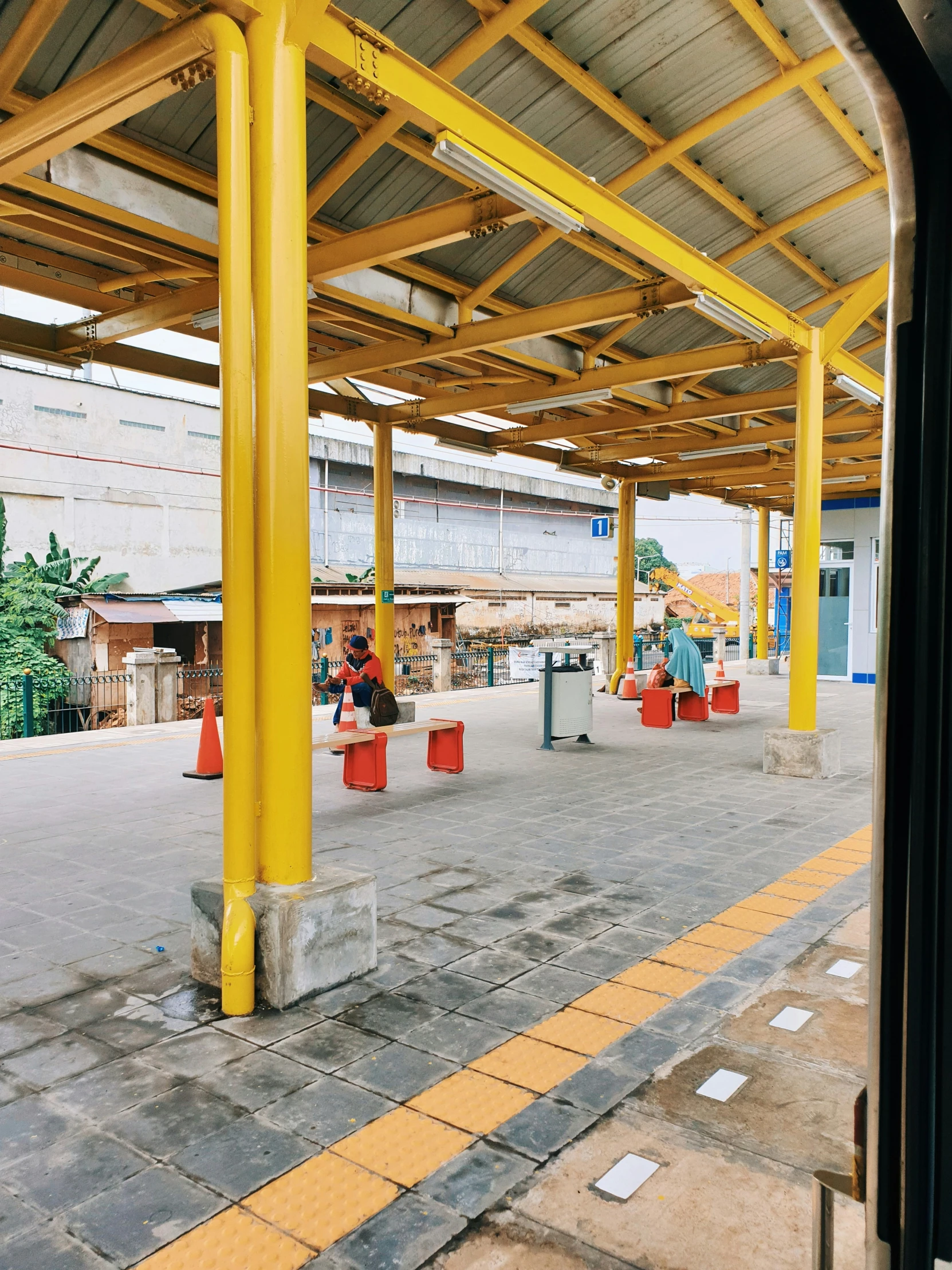 a man that is sitting on a bench under a roof