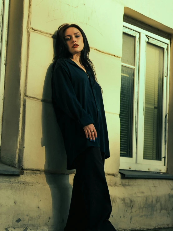 a woman standing against a wall in front of a window