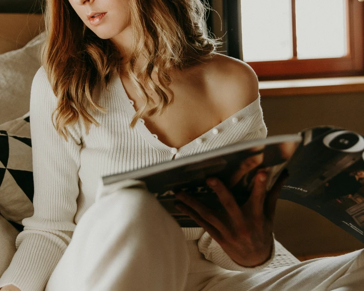 woman sitting on a bed reading a book