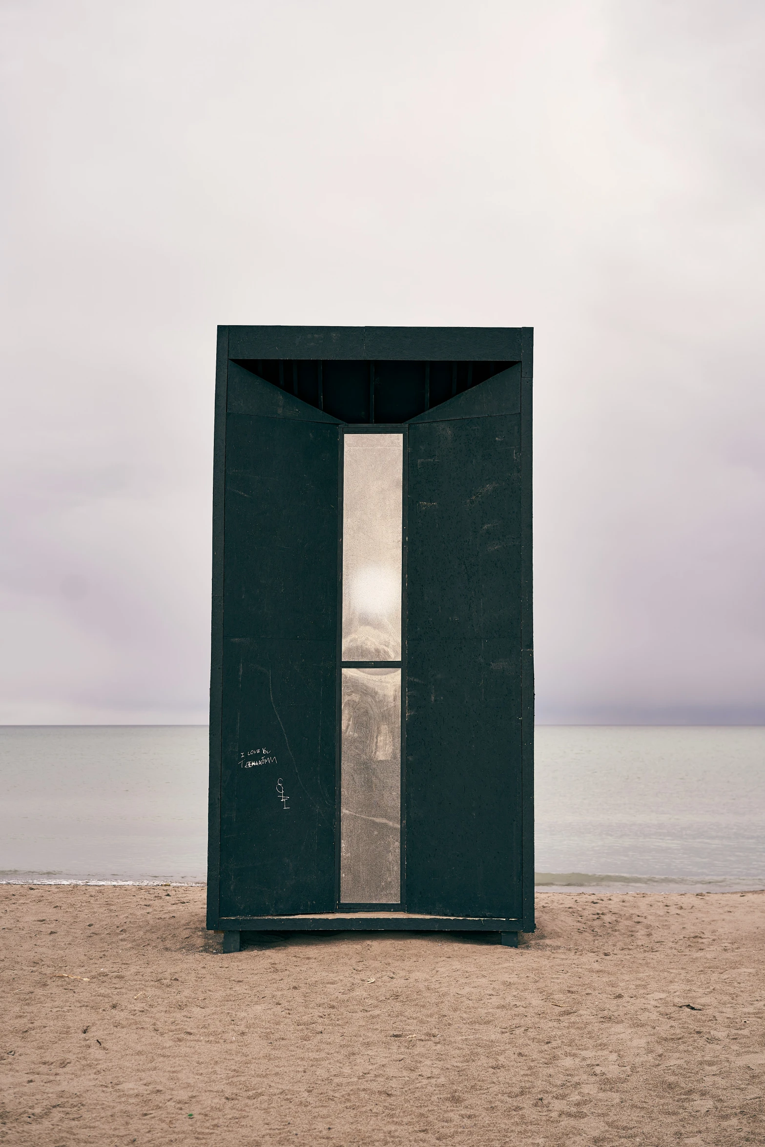 a small black building sitting next to the ocean