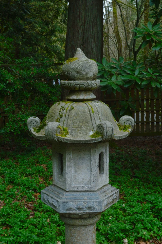 a cement lantern is in front of a tree