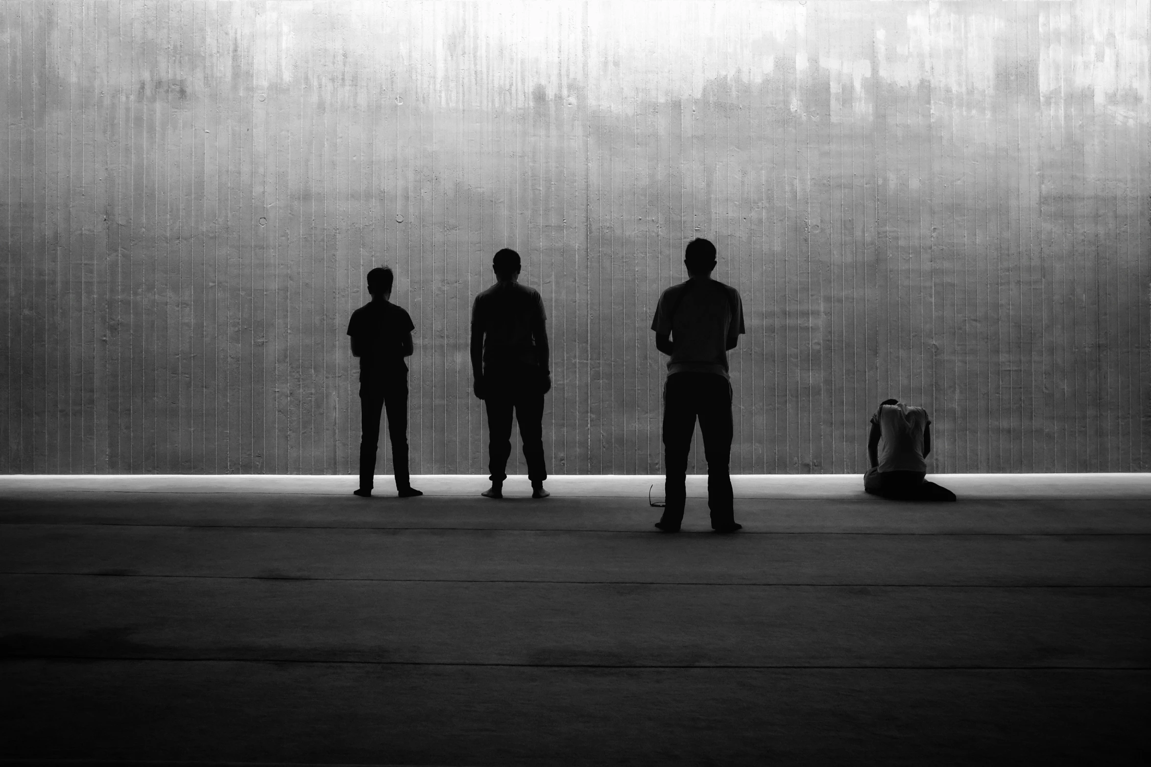 three men standing in front of a wall with the wall of the ground in front of them