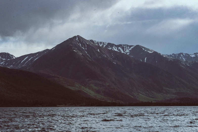 a boat traveling on the water in front of snowy mountains