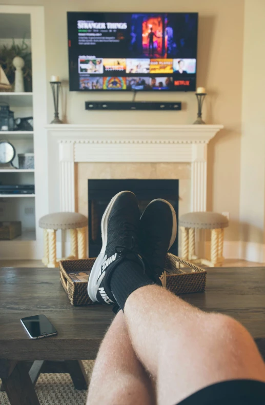 a man laying in front of the television while looking at the television