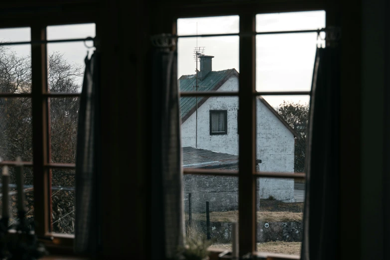 two windows with a view of a house through it