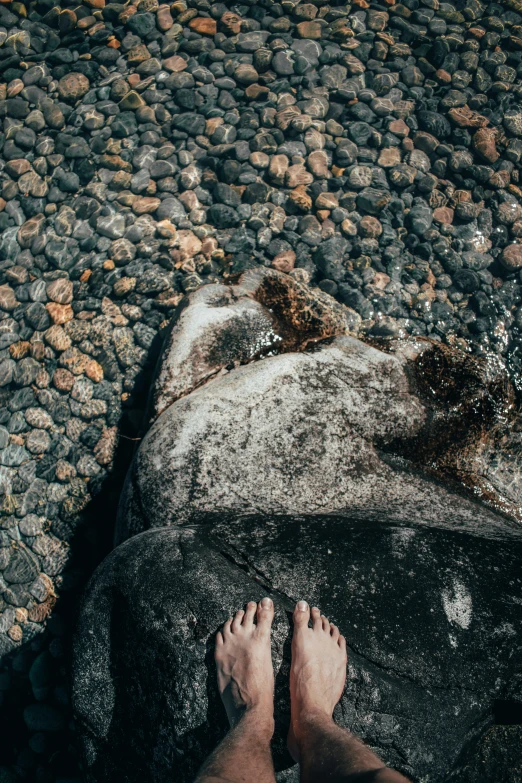 a person standing on a rocky beach next to water