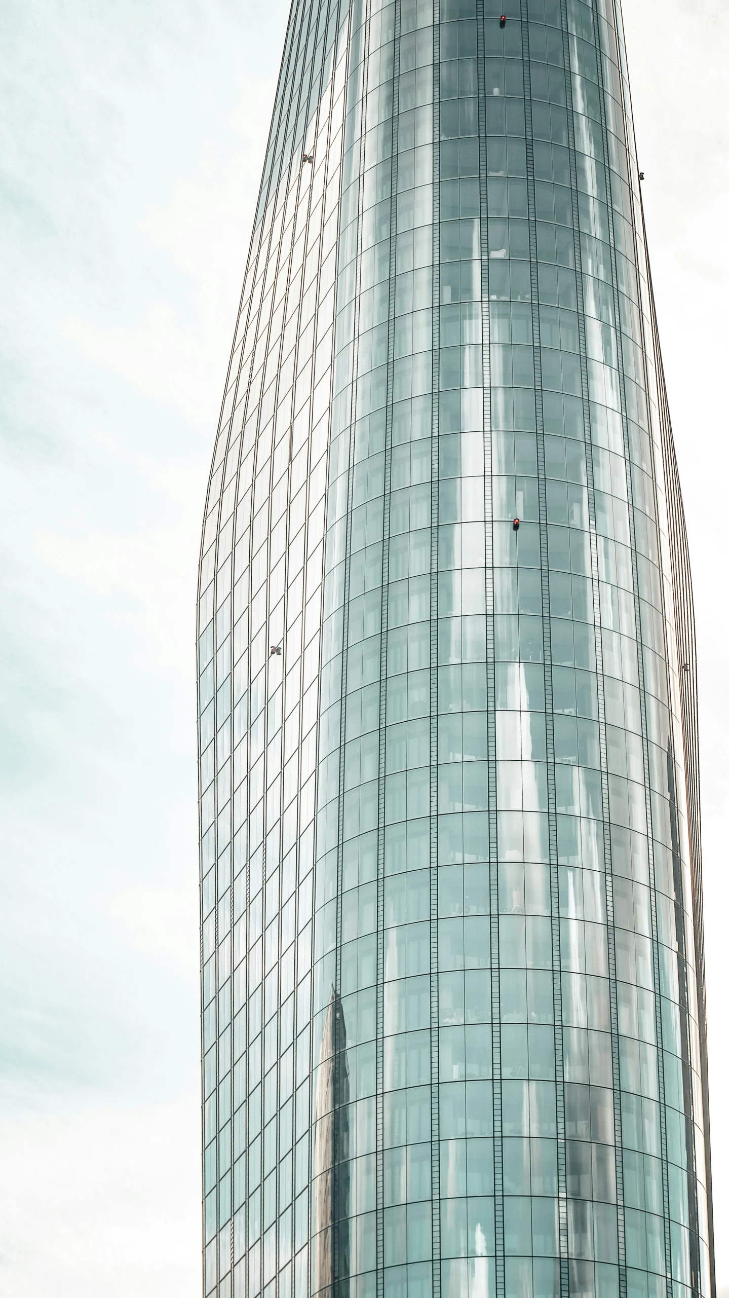 an unusual looking glass building with a clock on top