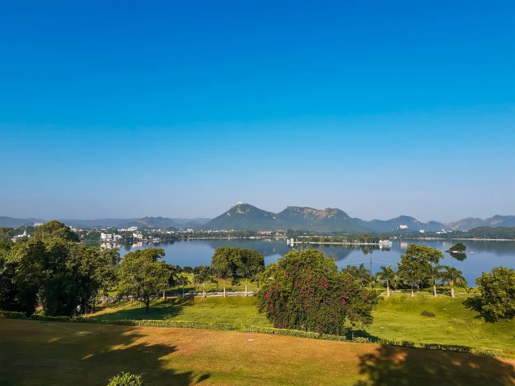 mountains on the horizon, water and trees near the grass