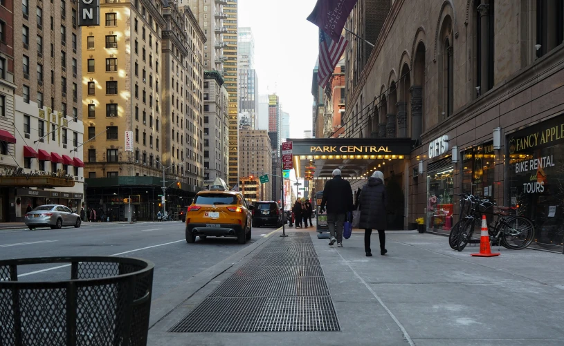 pedestrians walking down a street with tall buildings