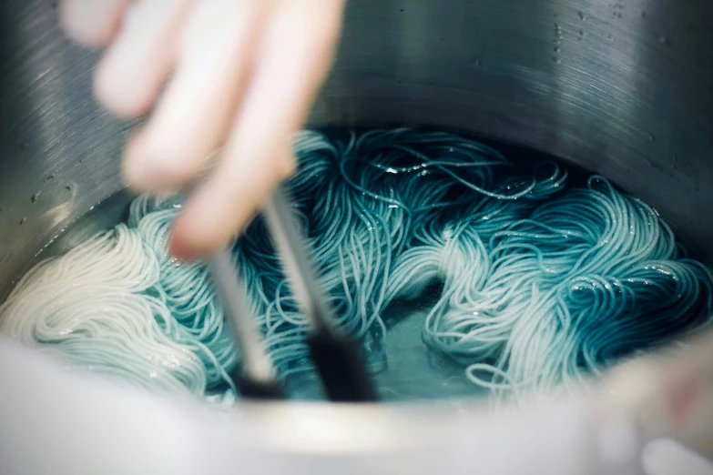 someone stirring yarn into an iron pot