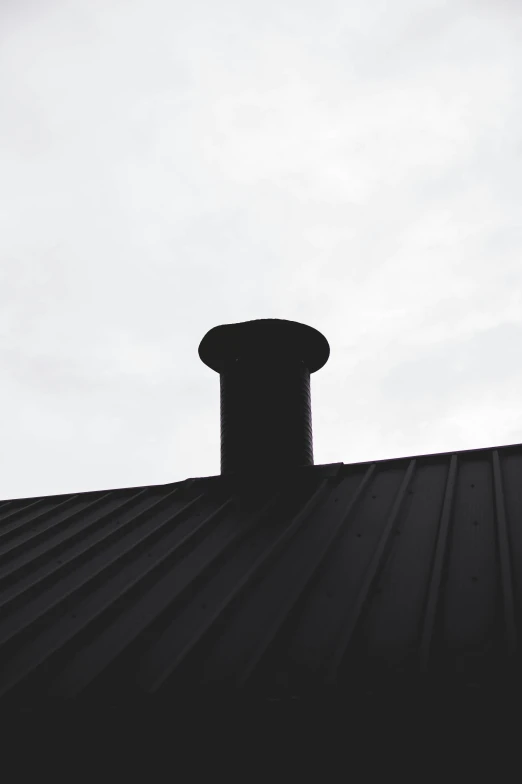 silhouetted building with smoke stack and sky background