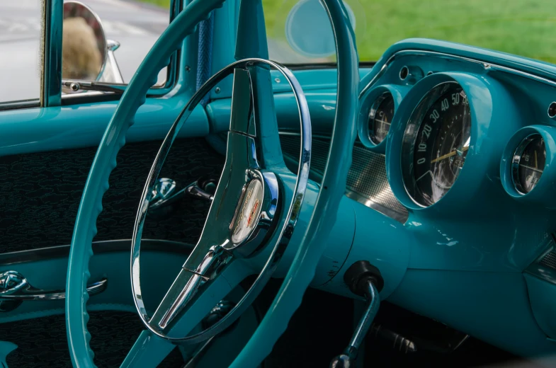 the dashboard of an old - school blue car with an unusual wooden steering wheel