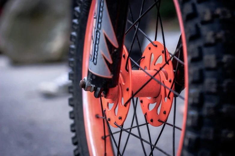 an orange bike wheel with spokes and black spokes