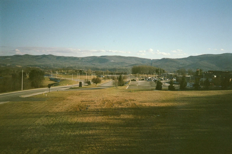 a street and car parked on a hill near a rural area