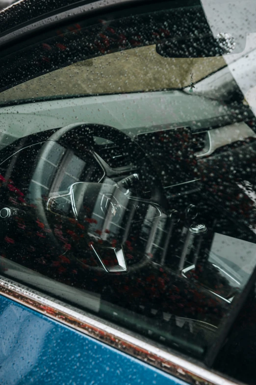 a blue car door with rain and red flowers reflecting in it