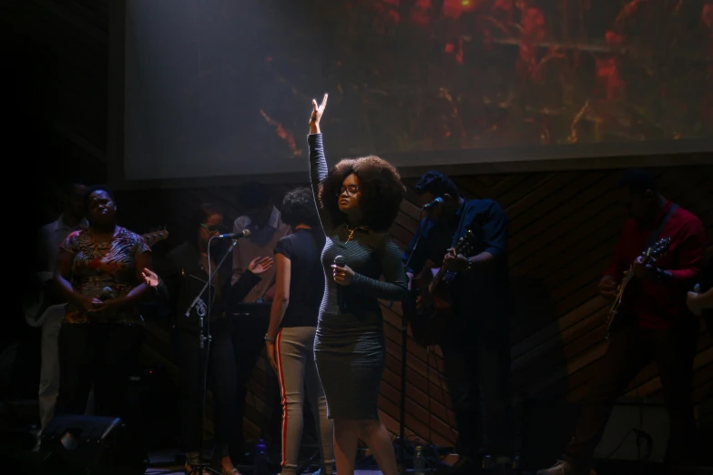 a singer on stage sings with her arm raised