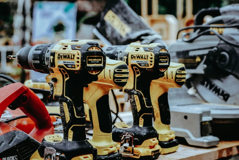 two cordless drillers on a table next to power tools