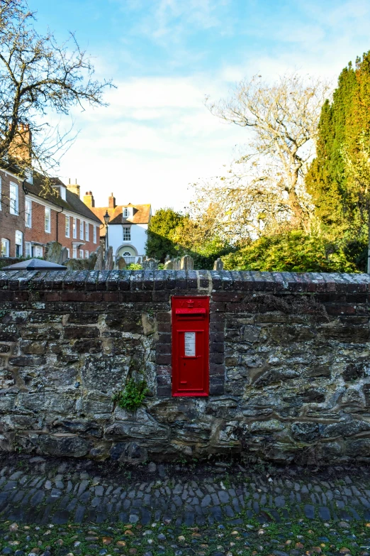 an old brick wall with a red post box on the top of it