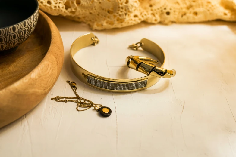 a pair of gold celets next to an ornate bowl