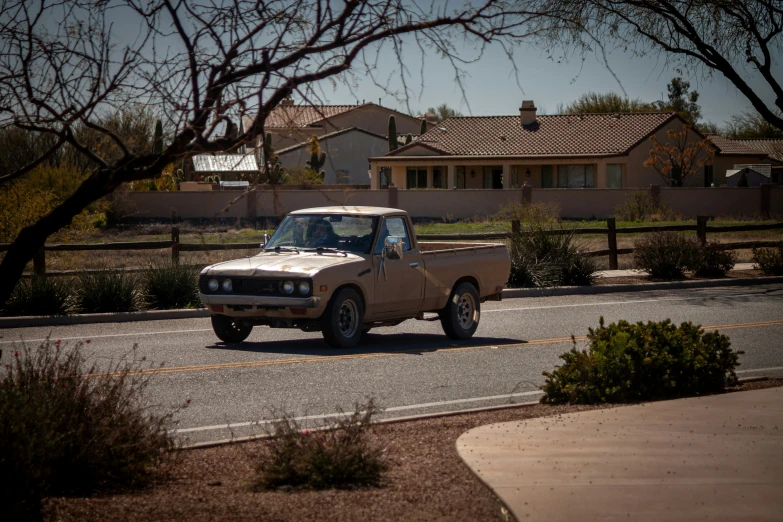 an older pickup truck is parked on the street near a fence