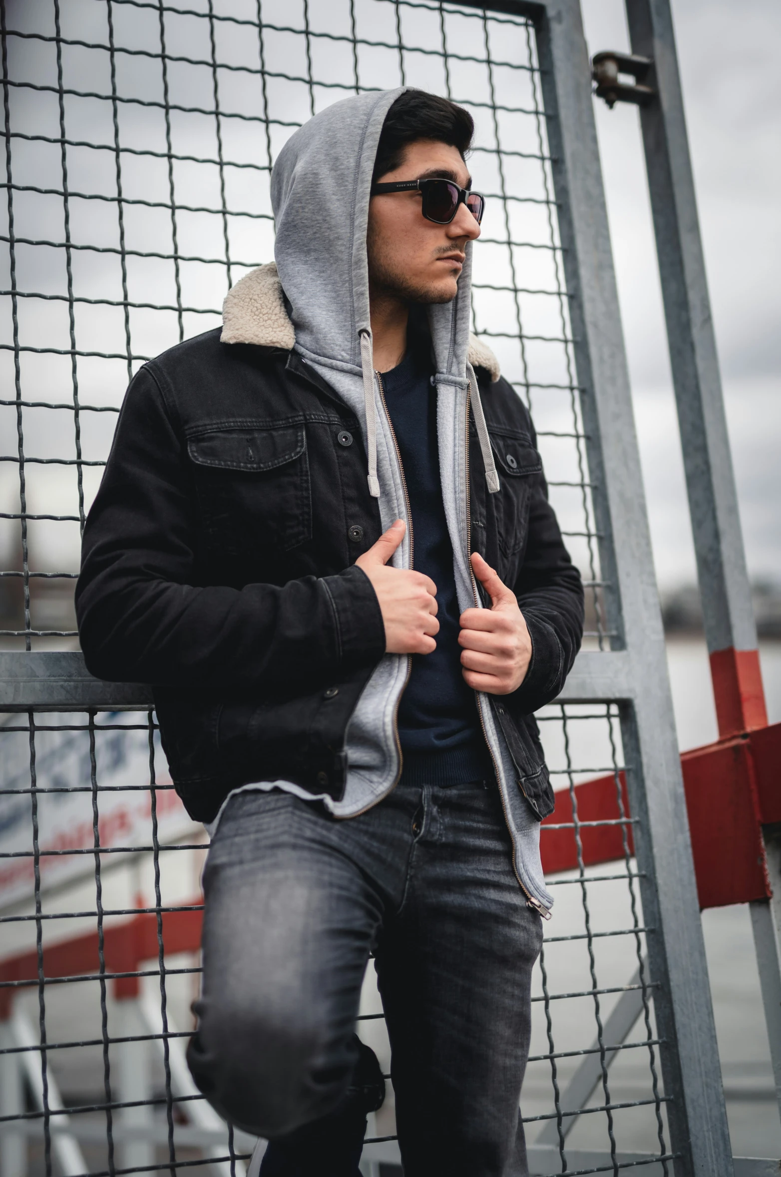 a man in sunglasses stands next to a fence