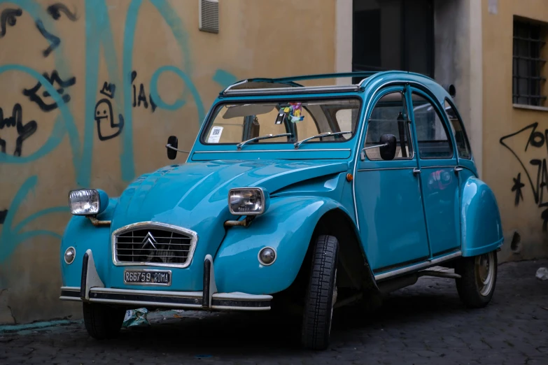 a blue car parked outside with graffiti on the walls