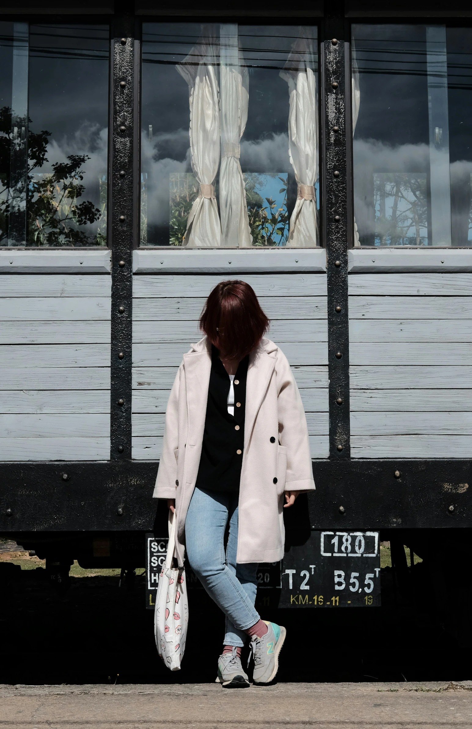 woman walking in front of train with bags on feet