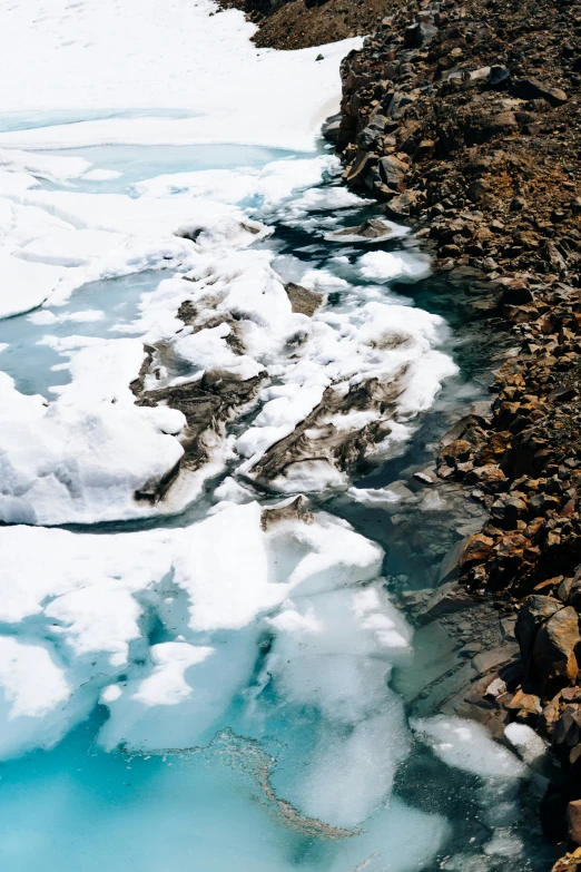 a path is made of ice and snow next to a rocky hillside