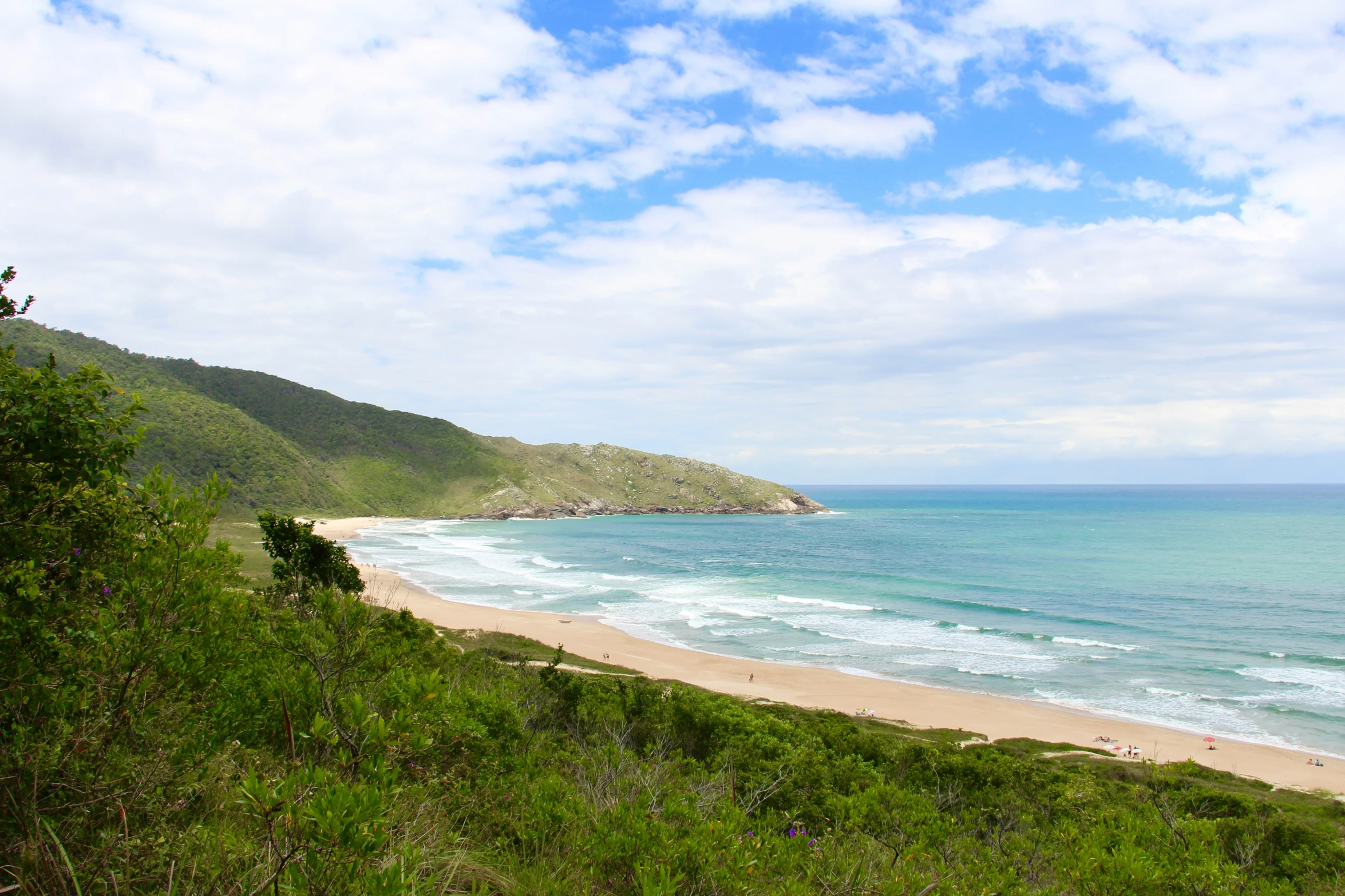 a beautiful beach with a couple of surfers out side