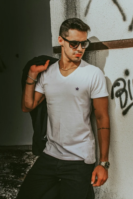 man in black shorts and white t - shirt standing against wall