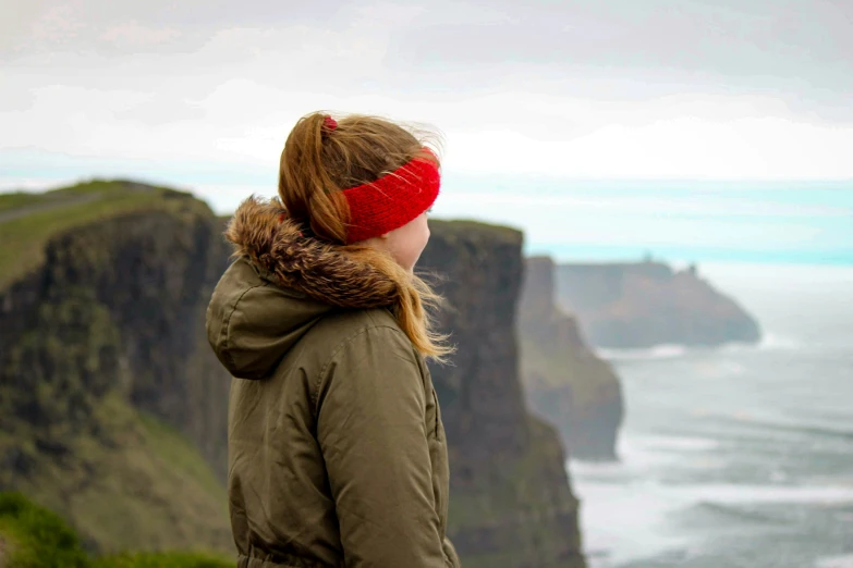 woman with red headband on overlooking ocean, cliffs and coastline