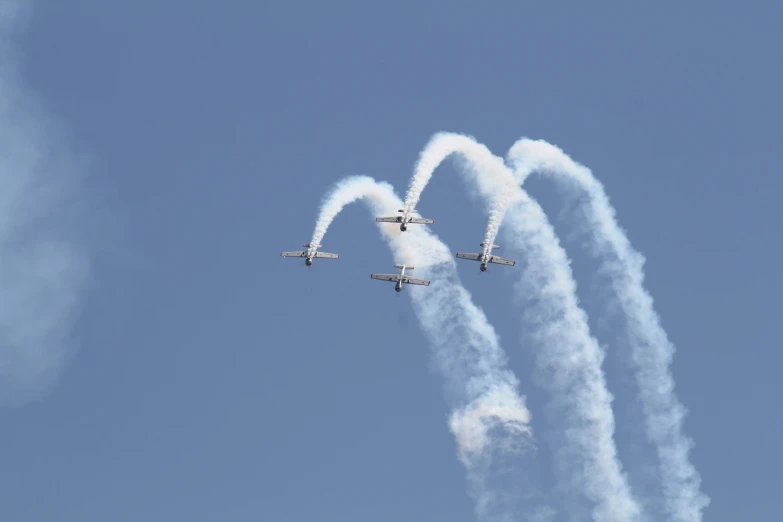 four airplanes flying in the air with smoke pouring out of them