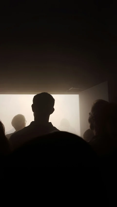 the dark silhouette of people standing in front of a wall