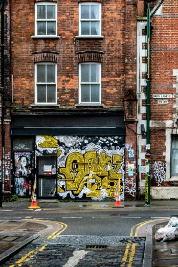 some yellow graffiti sitting on the side of a tall brick building