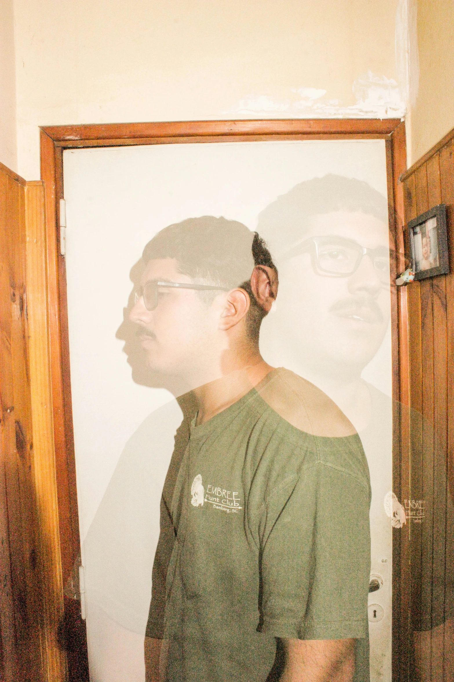 a man in a green shirt standing in front of a mirror