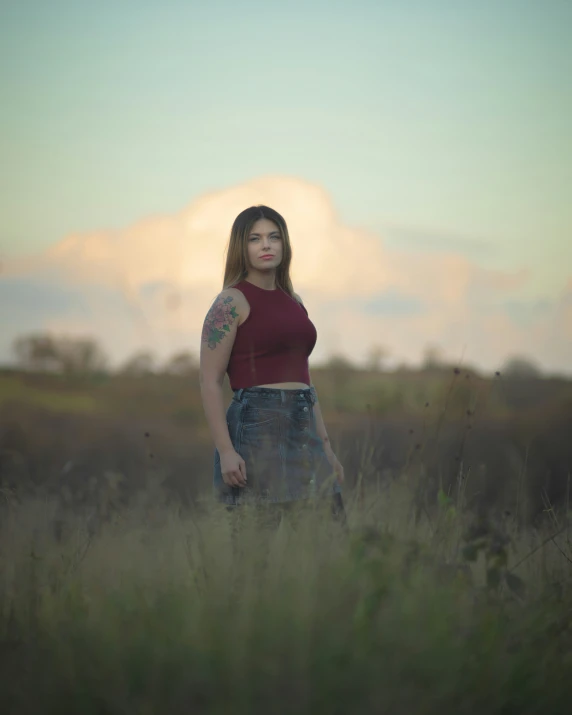 a woman with tattoo standing in a field