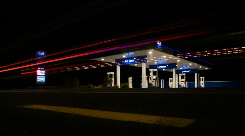 two gas pumps lit up at night near a gas station