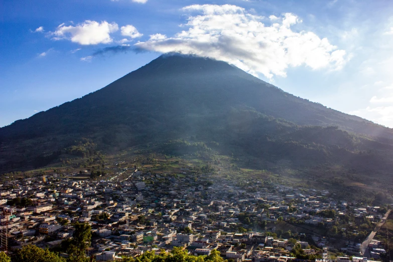 a city below a mountain on a sunny day