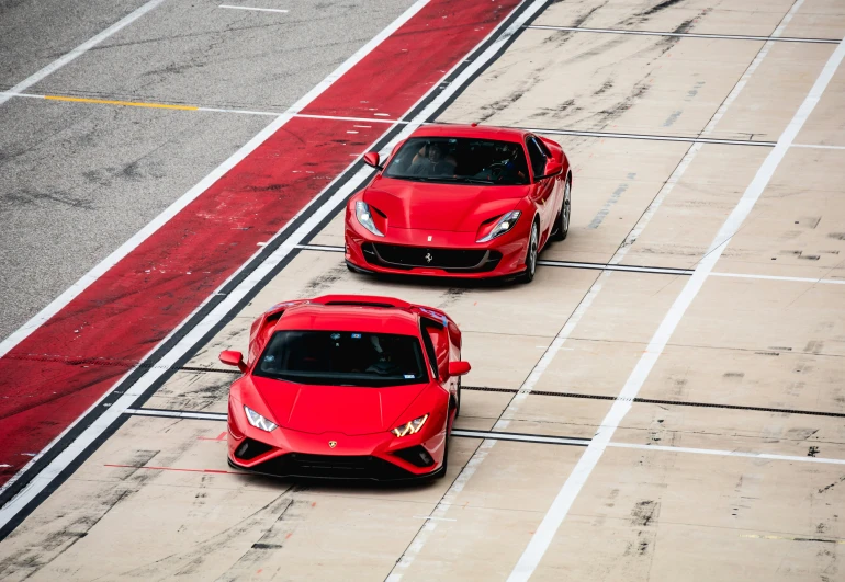 two sport cars on the track with the front of them painted red