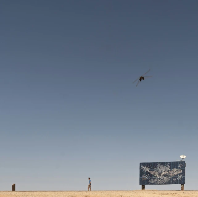 two people are standing on a sandy field and one is flying a kite